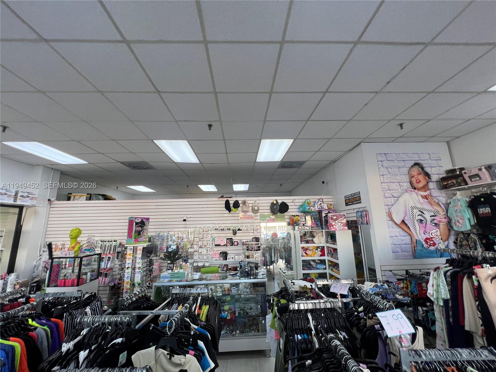 A retail store interior features clothing racks, display cases, and a large wall poster — 500 W 49th St, Hialeah FL 33012, HIALEAH, FL