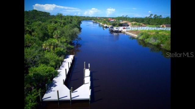 An aerial view shows a wooden boat dock extending into a calm, dark river — 1140 HOFFER STREET, PORT CHARLOTTE, FL