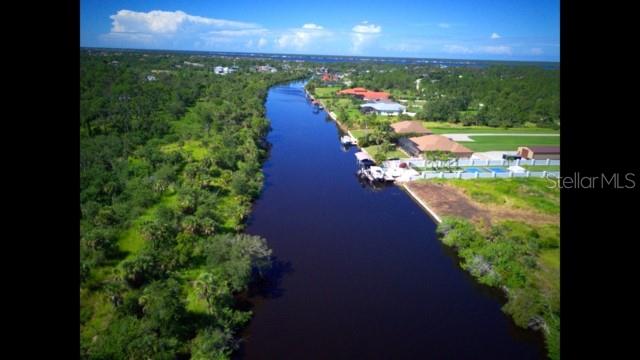 An aerial view shows a canal flowing past residential properties with docks and green vegetation — 1140 HOFFER STREET, PORT CHARLOTTE, FL