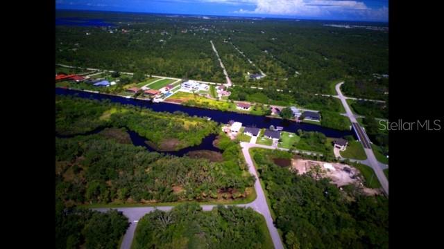 An aerial view shows a canal running through a wooded area with scattered residential houses — 1140 HOFFER STREET, PORT CHARLOTTE, FL