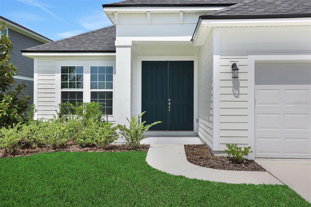 A white house exterior features a dark blue double front door and a concrete walkway — 3932 HOLSTEIN WAY, GREEN COVE SPRINGS, FL