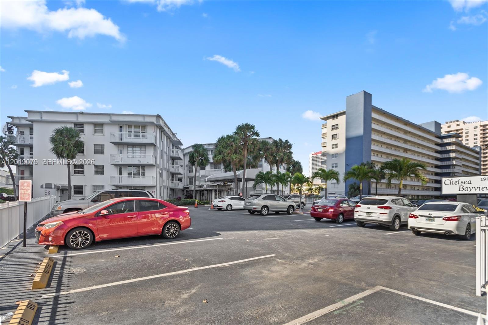 A parking lot sits in front of two multi-story apartment buildings with palm trees — 1913 S Ocean Dr # 212, Hallandale Beach FL 33009, HALLANDALE BEACH, FL