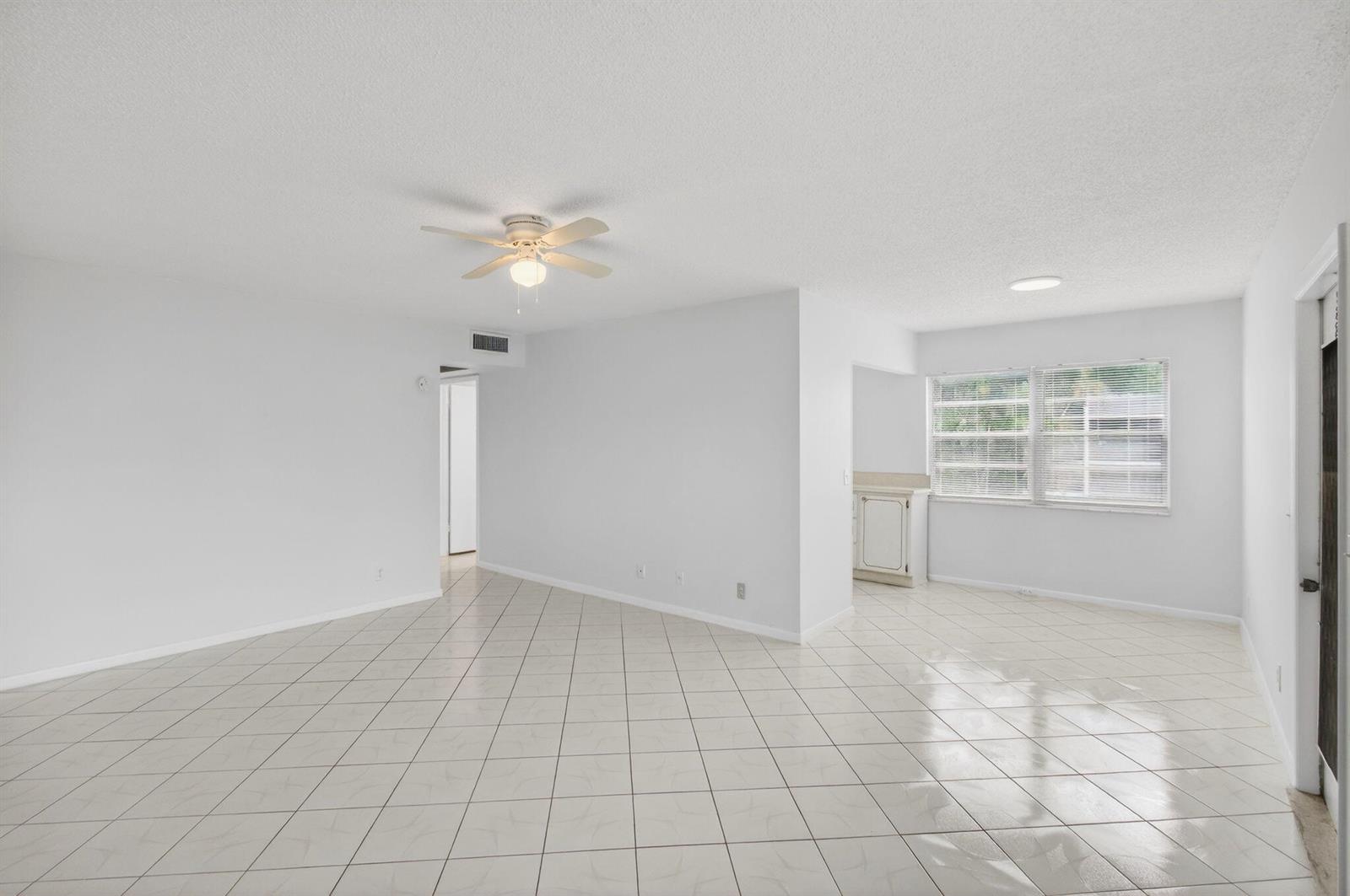 An open-concept living area features white walls, a ceiling fan, and light-colored diagonal floor tiles — 360 Fanshaw I, Boca Raton FL 33434, BOCA RATON, FL