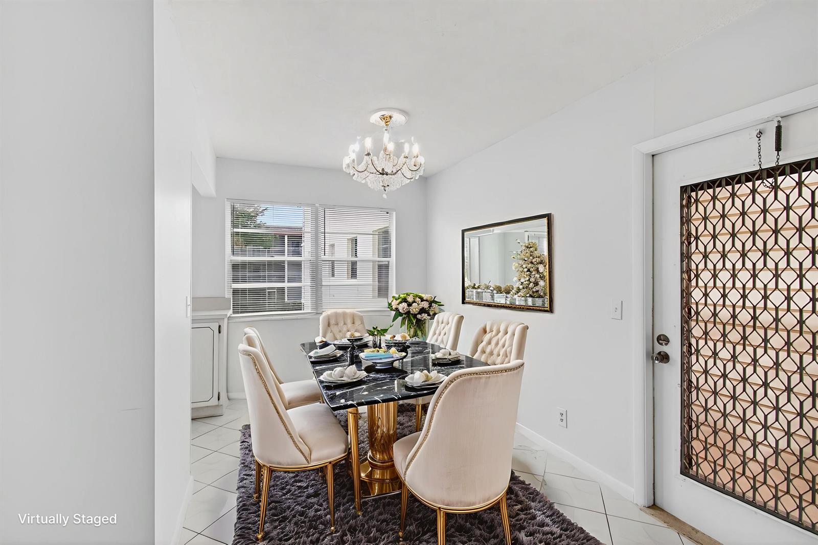 A dining room with a marble table, tufted chairs, a chandelier, and a security door — 360 Fanshaw I, Boca Raton FL 33434, BOCA RATON, FL