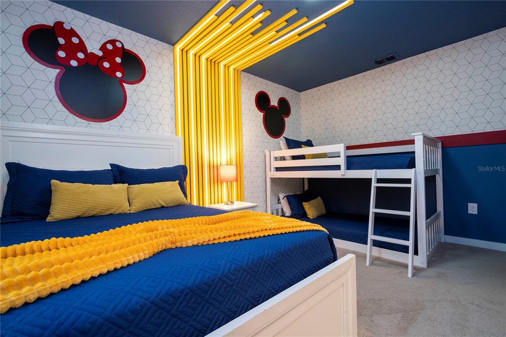 A bedroom features a large bed, bunk beds, Mickey Mouse wall art, and yellow ceiling slats — 3369 TRANQUIL TRAIL, KISSIMMEE, FL
