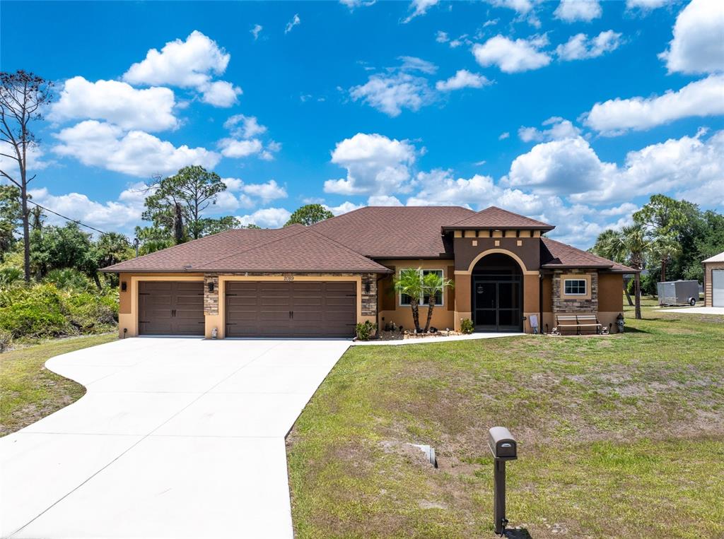 A single-story house with a brown roof, tan stucco walls, and a three-car garage — 2089 MAUVE TERRACE, NORTH PORT, FL