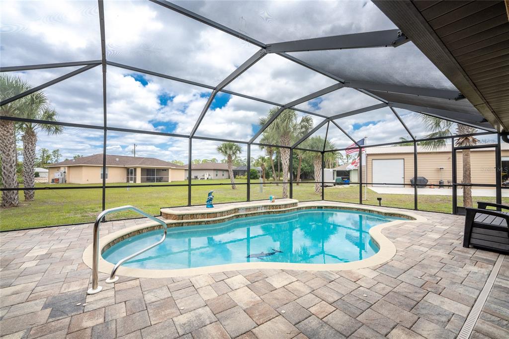 A screened-in patio features a kidney-shaped swimming pool with a stone-accented water feature — 2089 MAUVE TERRACE, NORTH PORT, FL