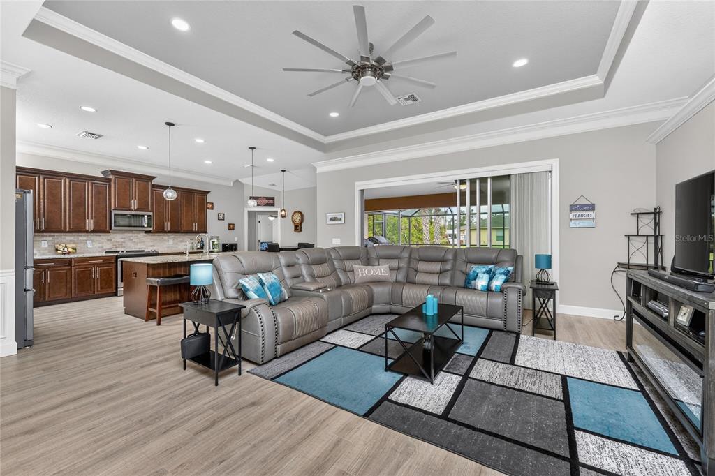 A living room with a gray sectional sofa, geometric area rug, and an open-concept kitchen — 2089 MAUVE TERRACE, NORTH PORT, FL
