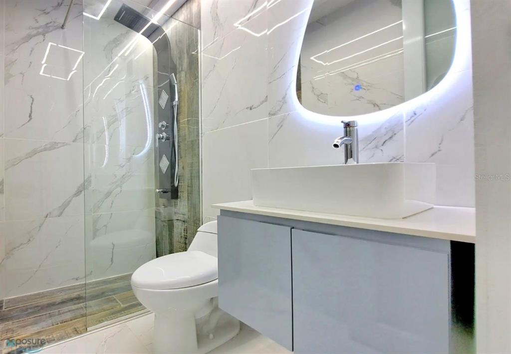 A modern bathroom features a glass-enclosed shower, a white vessel sink, and marble-patterned wall tiles — APT 6 A CARR 833 UNIT 6a, GUAYNABO, PR