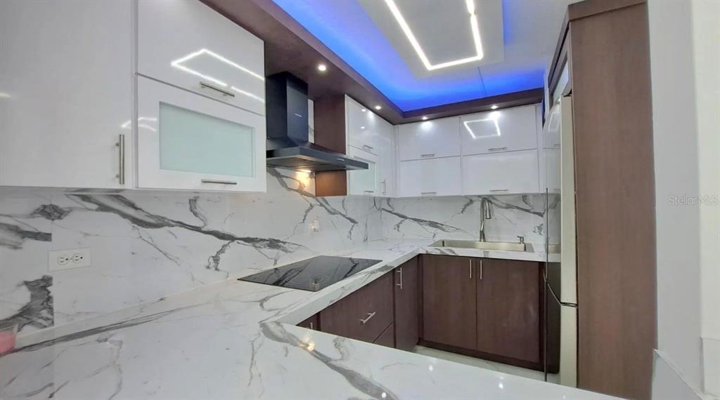 A modern kitchen features white cabinets, marble-patterned countertops, and blue accent lighting — APT 6 A CARR 833 UNIT 6a, GUAYNABO, PR