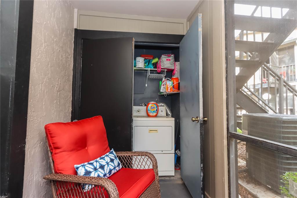 A patio features a wicker chair with red cushions and an open laundry closet — 4009 NESTLE OAKS PLACE UNIT 104, TAMPA, FL