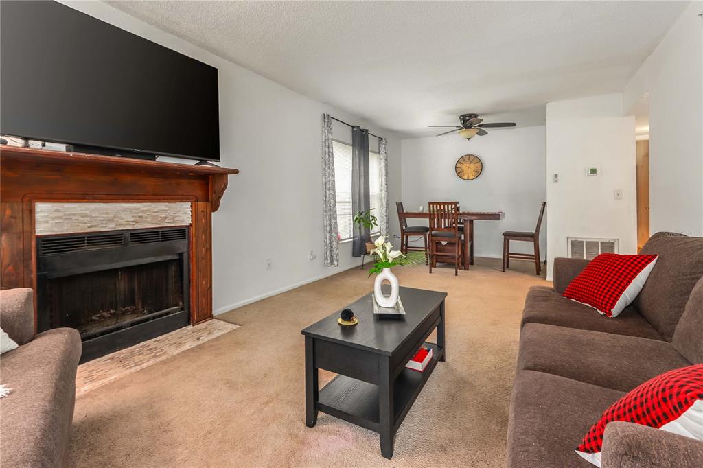 A living room features a fireplace with a wooden mantel, a television, and dining area — 4009 NESTLE OAKS PLACE UNIT 104, TAMPA, FL