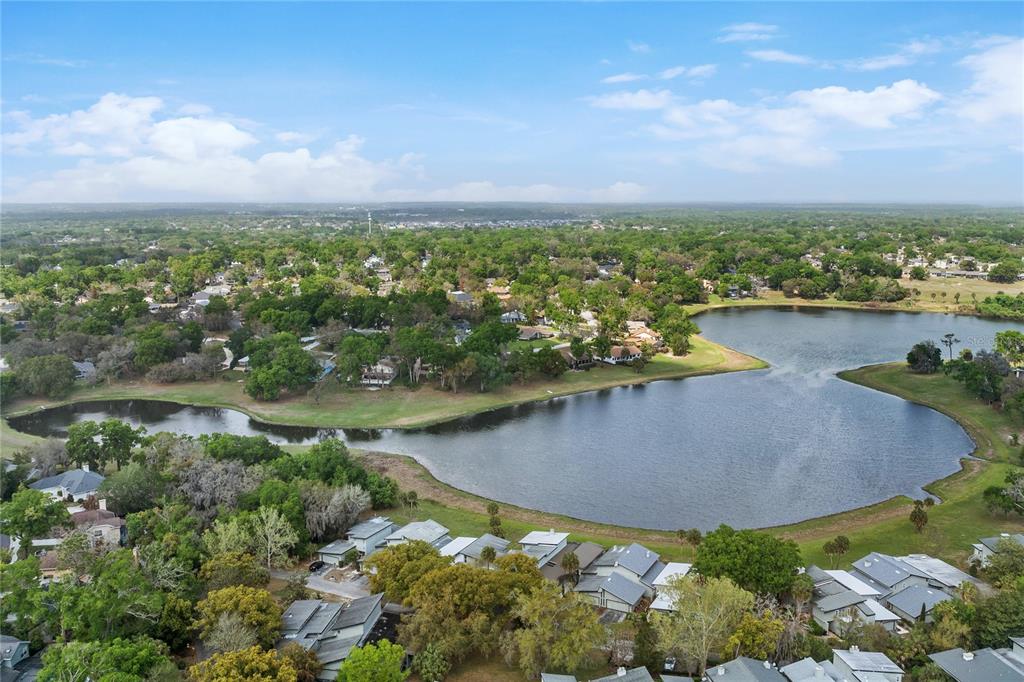 An aerial view shows a lake surrounded by residential houses and lush green trees — 1318 CHEBON CT COURT Unit E-F, APOPKA, FL