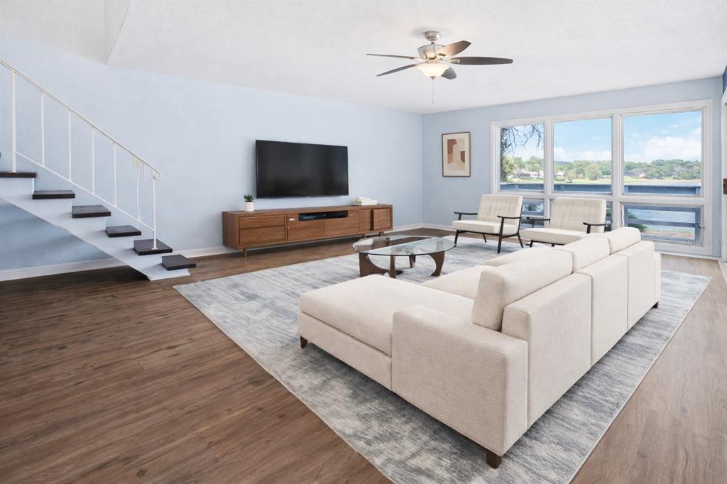 A living room features light blue walls, wood flooring, a staircase, and large windows — 1318 CHEBON CT COURT Unit E-F, APOPKA, FL