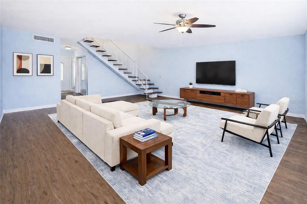 A living room features light blue walls, a white sectional, two armchairs, and a staircase — 1318 CHEBON CT COURT Unit E-F, APOPKA, FL