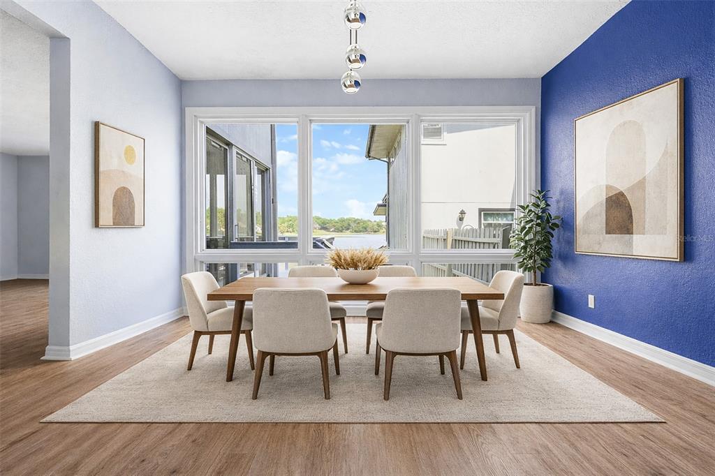 A dining room features a wooden table, six chairs, and a large window overlooking water — 1318 CHEBON CT COURT Unit E-F, APOPKA, FL