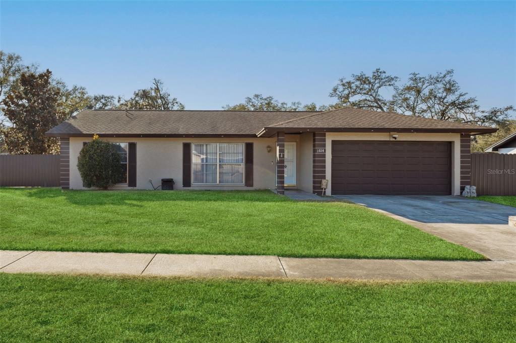 A single-story house with a brown roof, tan stucco exterior, and a two-car garage — 1614 BERKSHIRE DRIVE, BRANDON, FL