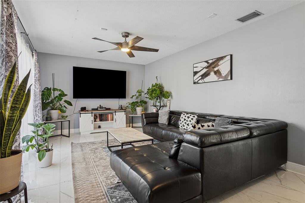 A living room features a black sectional sofa, a television, and a ceiling fan — 1614 BERKSHIRE DRIVE, BRANDON, FL
