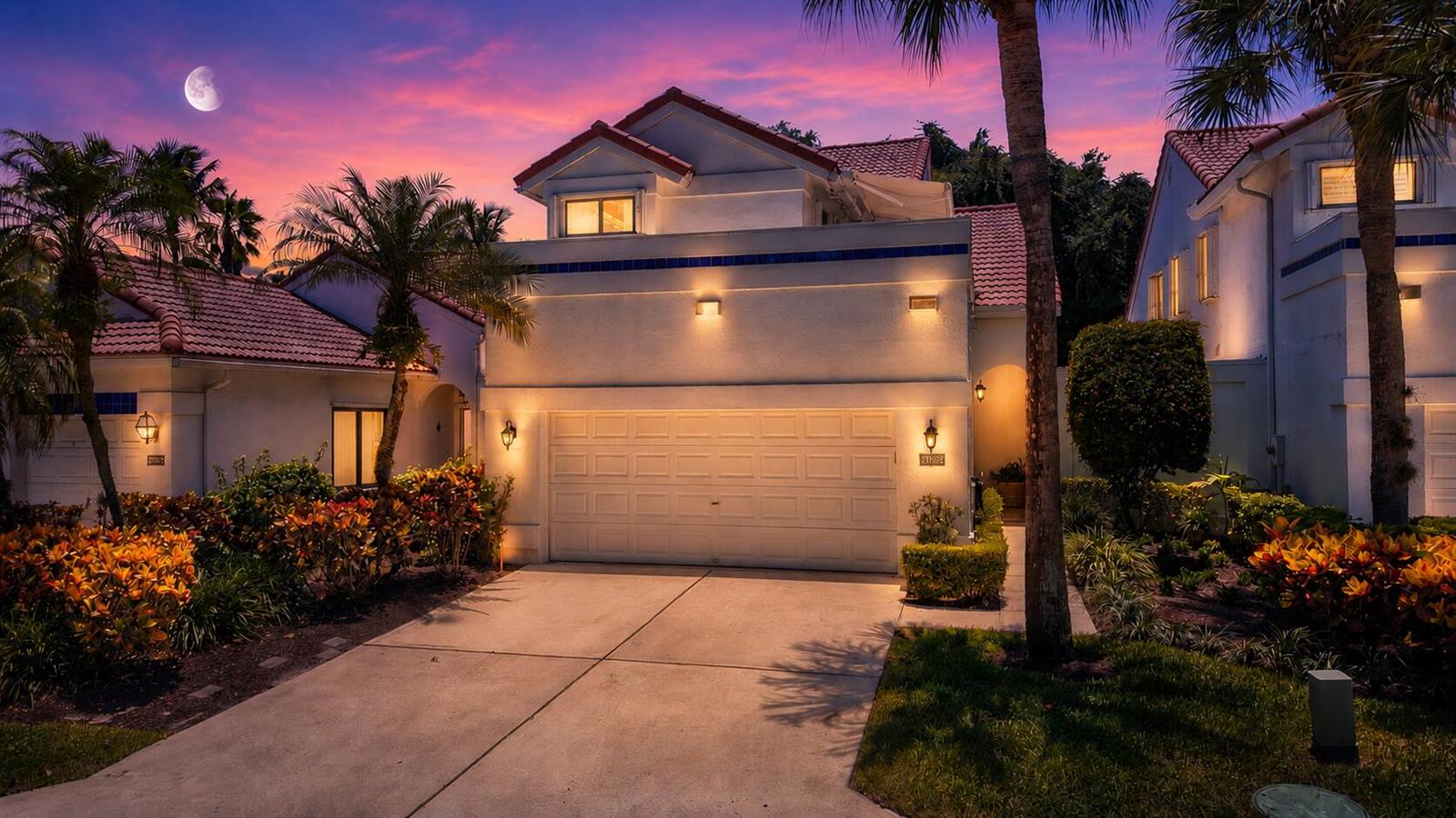 A two-story house with a white stucco exterior, a garage, and palm trees at dusk — 21692 Cromwell Circle, Boca Raton FL 33486, BOCA RATON, FL