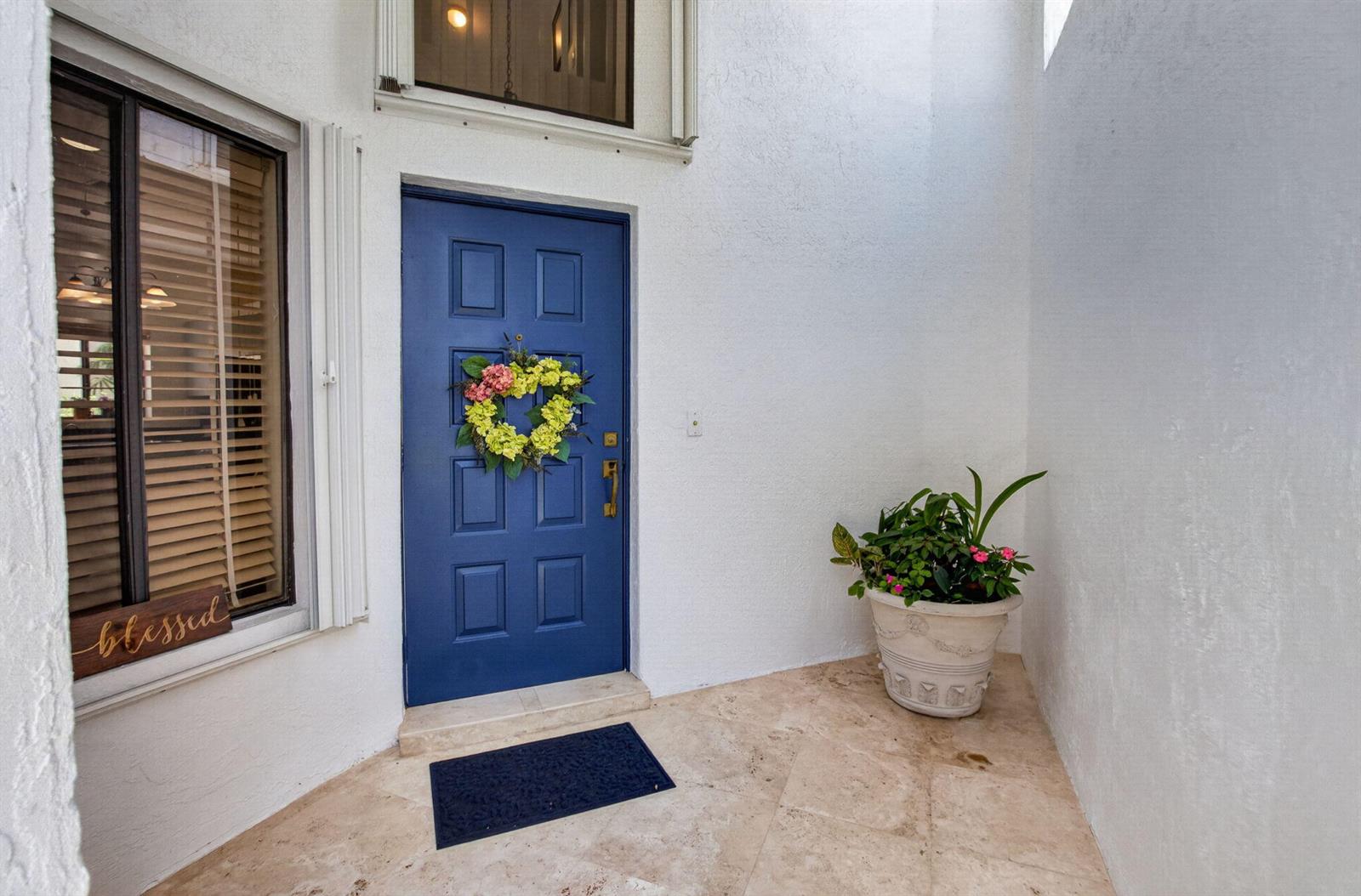 A blue front door with a wreath sits on a tiled porch with a planter — 21692 Cromwell Circle, Boca Raton FL 33486, BOCA RATON, FL