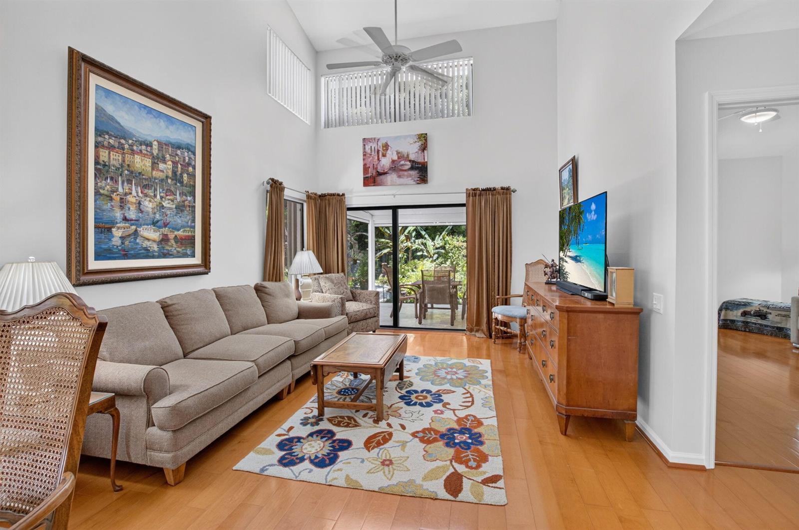 A living room features high ceilings, a beige sofa, a floral rug, and sliding glass doors — 21692 Cromwell Circle, Boca Raton FL 33486, BOCA RATON, FL