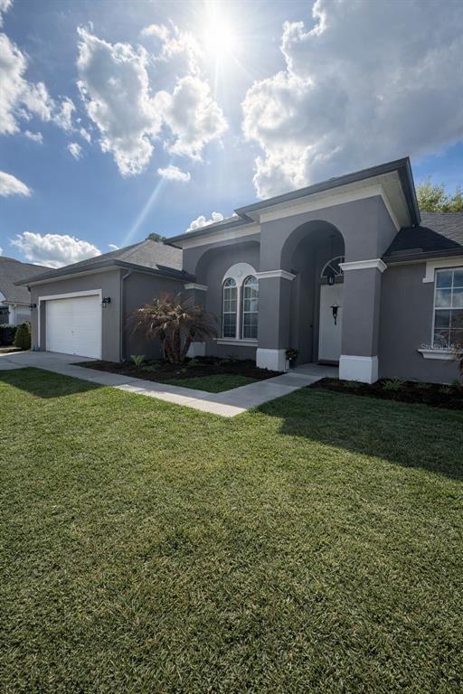 A gray single-story house with a white garage door, arched entryway, and a green lawn — 2240 BAGDAD AVENUE, ORLANDO, FL