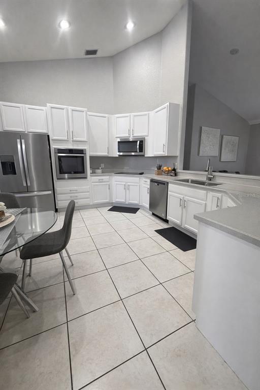 A kitchen features white cabinets, stainless steel appliances, and light tile flooring — 2240 BAGDAD AVENUE, ORLANDO, FL