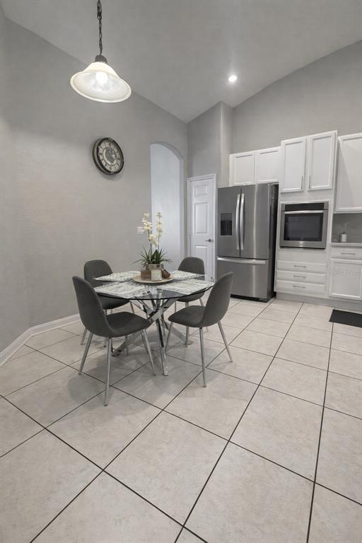 A dining area with a glass table, four chairs, and an adjacent kitchen with white cabinets — 2240 BAGDAD AVENUE, ORLANDO, FL