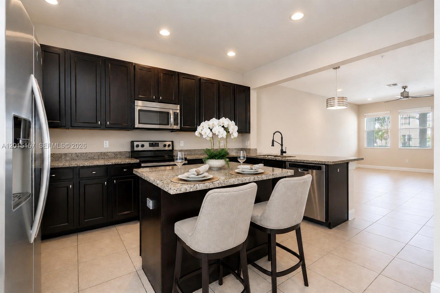 A kitchen features dark wood cabinets, granite countertops, a center island, and stainless steel appliances — 2709 SW 119th Way # 2709, Miramar FL 33025, MIRAMAR, FL