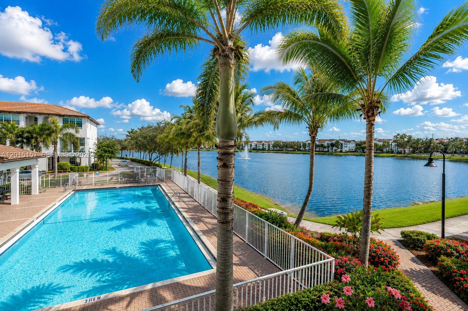 A swimming pool sits beside a lake with palm trees and apartment buildings in view — 2709 SW 119th Way # 2709, Miramar FL 33025, MIRAMAR, FL