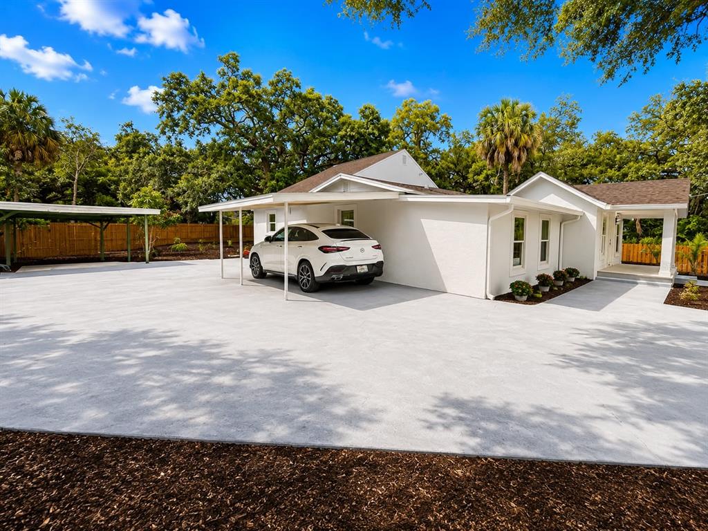 A white house with a carport and a large concrete driveway under a blue sky — 4311 N 25TH STREET, TAMPA, FL