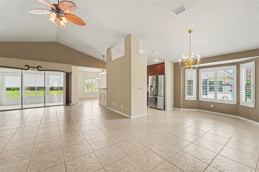 An open-concept living area with tiled floors, a kitchen island, and a vaulted ceiling — 3805 E KIWI COVE CT, HERNANDO, FL