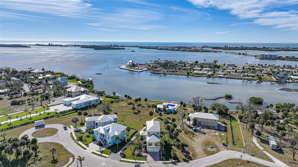 An aerial view shows several coastal houses situated along a bay with a distant bridge — 6751 PORTSIDE LANE, ENGLEWOOD, FL