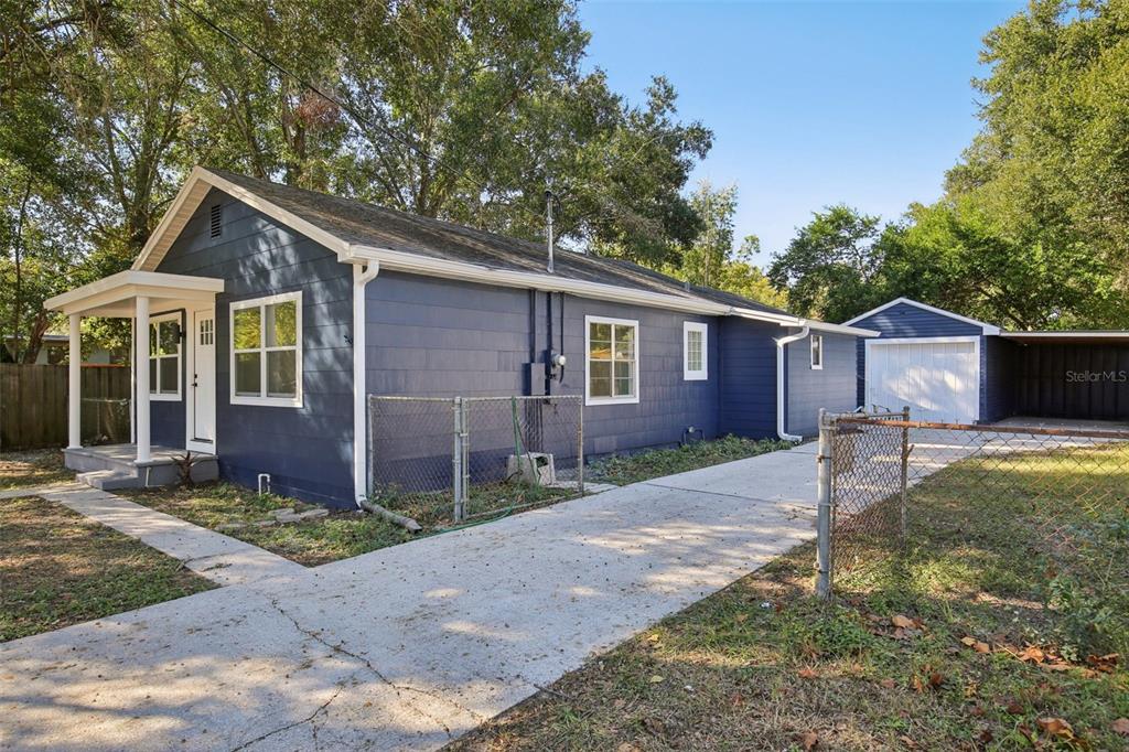 A blue house with a white-trimmed porch, a concrete driveway, and a detached garage — 5808 N 17TH STREET, TAMPA, FL