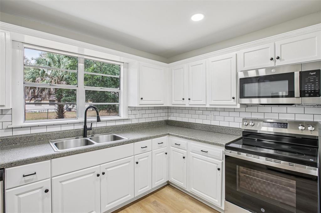 A kitchen with white cabinets, gray countertops, a subway tile backsplash, and stainless steel appliances — 5808 N 17TH STREET, TAMPA, FL