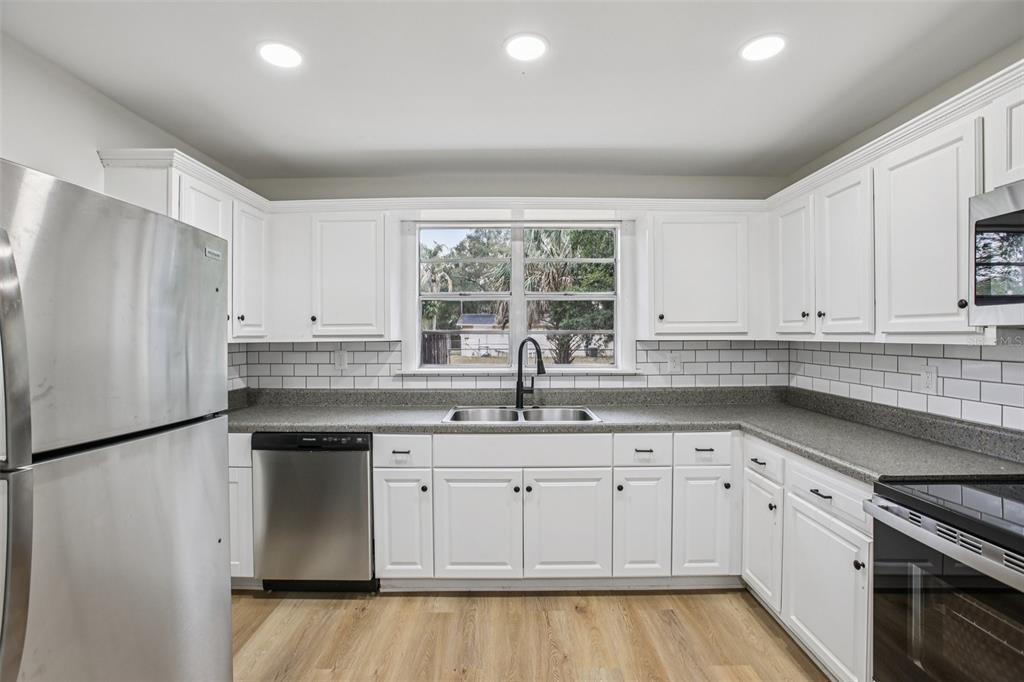 A kitchen with white cabinets, stainless steel appliances, gray countertops, and a subway tile backsplash — 5808 N 17TH STREET, TAMPA, FL