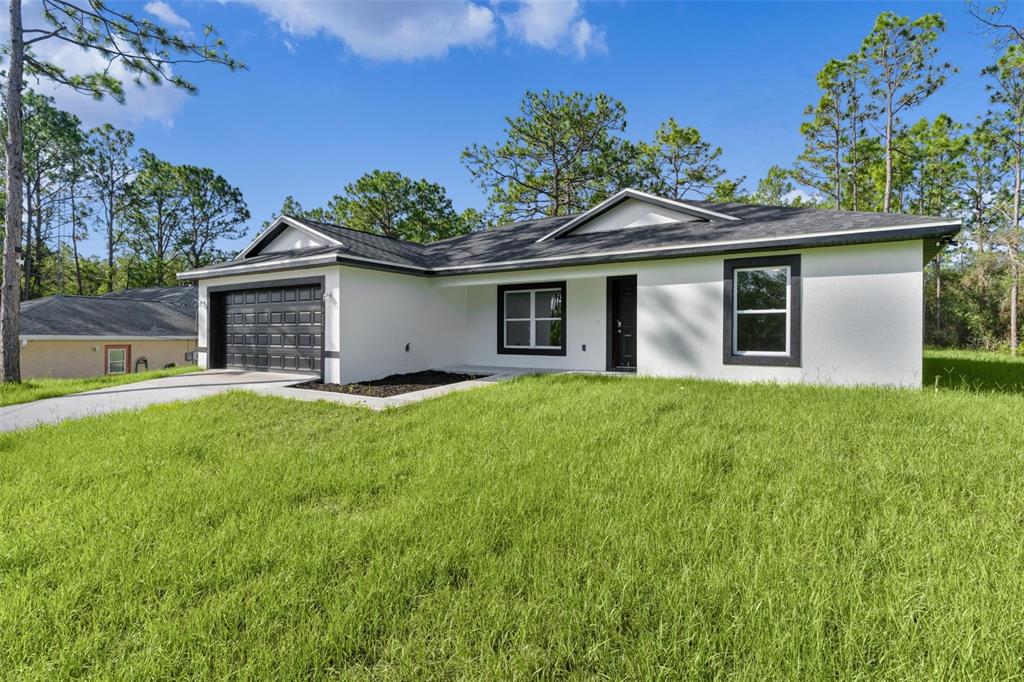 A single-story white house with a black roof, garage door, and window trim — 3228 W CAMILO DRIVE, CITRUS SPRINGS, FL