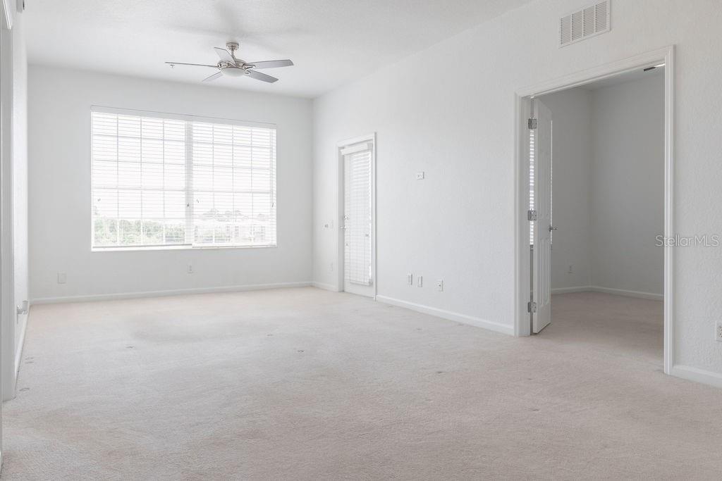 An empty room with white walls, beige carpeting, a ceiling fan, and two doorways — 3868 LEXMARK LANE UNIT 409, ROCKLEDGE, FL