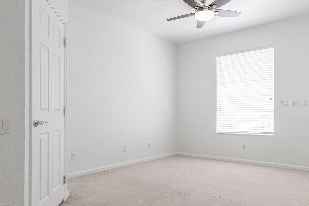 An empty bedroom with white walls, beige carpet, a ceiling fan, and a window — 3868 LEXMARK LANE UNIT 409, ROCKLEDGE, FL