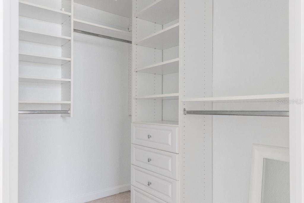 A walk-in closet features white shelving, a hanging rod, and a built-in drawer unit — 3868 LEXMARK LANE UNIT 409, ROCKLEDGE, FL