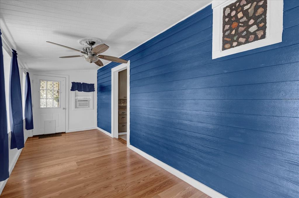 A sunroom features blue horizontal wood-paneled walls, light wood flooring, and a ceiling fan — 14043 TENNESSEE AVENUE, ASTATULA, FL