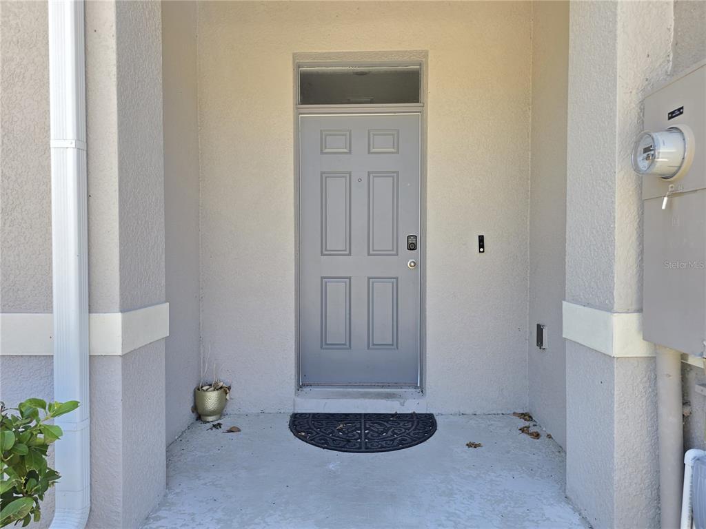 A gray front door with a transom window is set within a covered concrete entryway — 1242 LIDO DRIVE, HOWEY IN THE HILLS, FL
