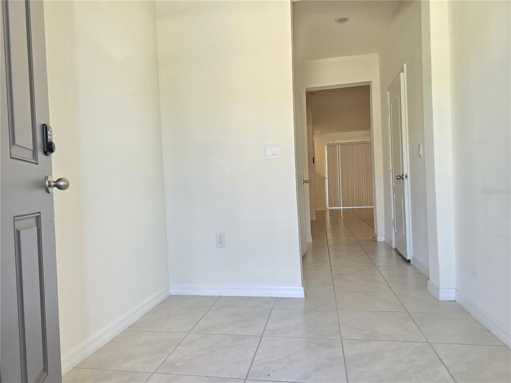 An entryway with light-colored tile flooring leads into a hallway with white walls — 1242 LIDO DRIVE, HOWEY IN THE HILLS, FL