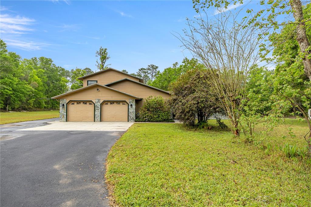 A two-story house with tan siding, a two-car garage, and a paved driveway — 20190 SW 54TH STREET, DUNNELLON, FL