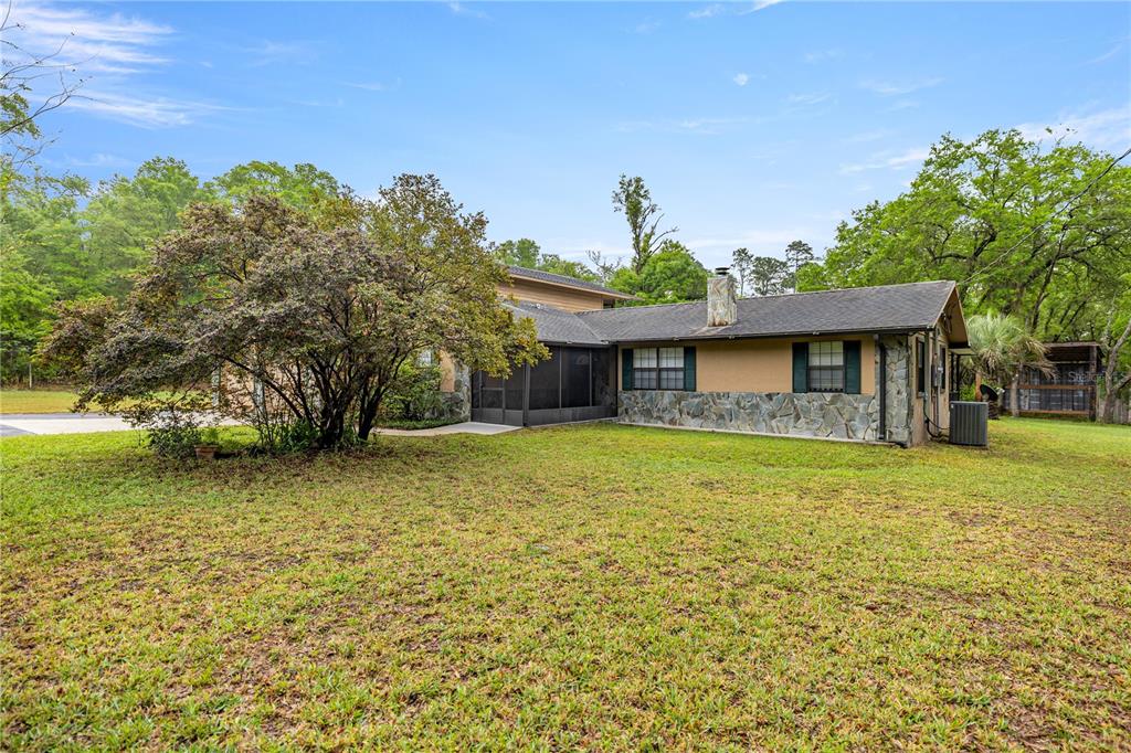 A single-story house with a stone facade, a screened-in porch, and a large tree — 20190 SW 54TH STREET, DUNNELLON, FL