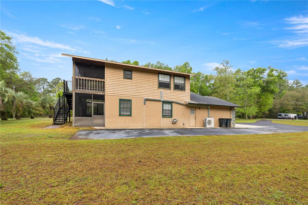 The exterior of a two-story house features tan siding, a screened-in porch, and a driveway — 20190 SW 54TH STREET, DUNNELLON, FL