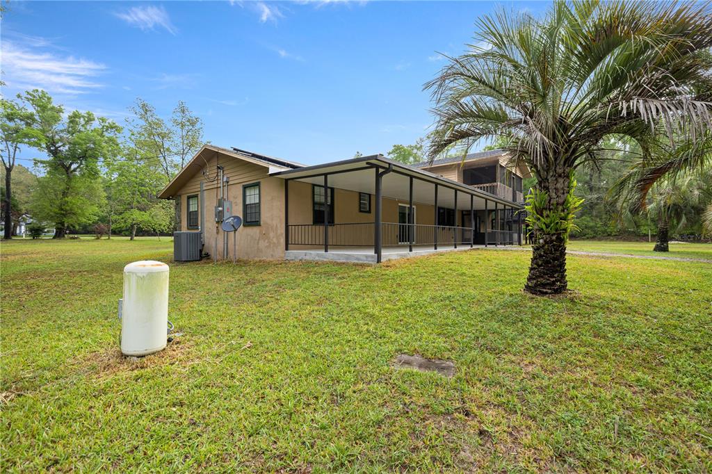 A tan house with a large covered porch and a palm tree in the yard — 20190 SW 54TH STREET, DUNNELLON, FL
