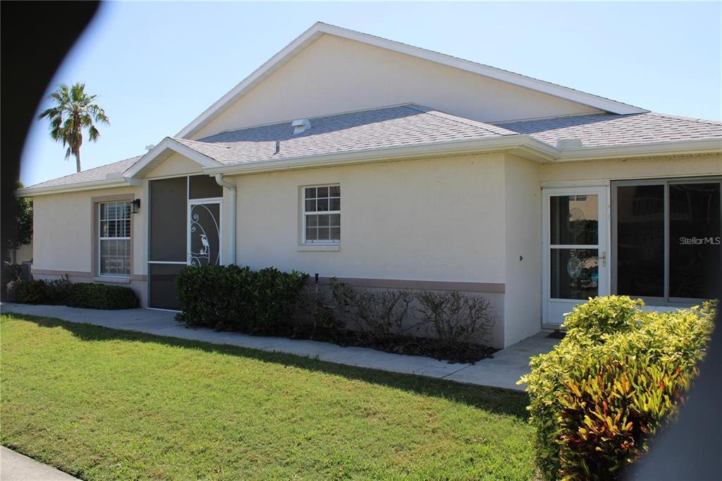 A single-story house with a beige stucco exterior, a screened porch, and a grassy lawn — 1702 FAIRWAY TRACE UNIT 1702, PALMETTO, FL
