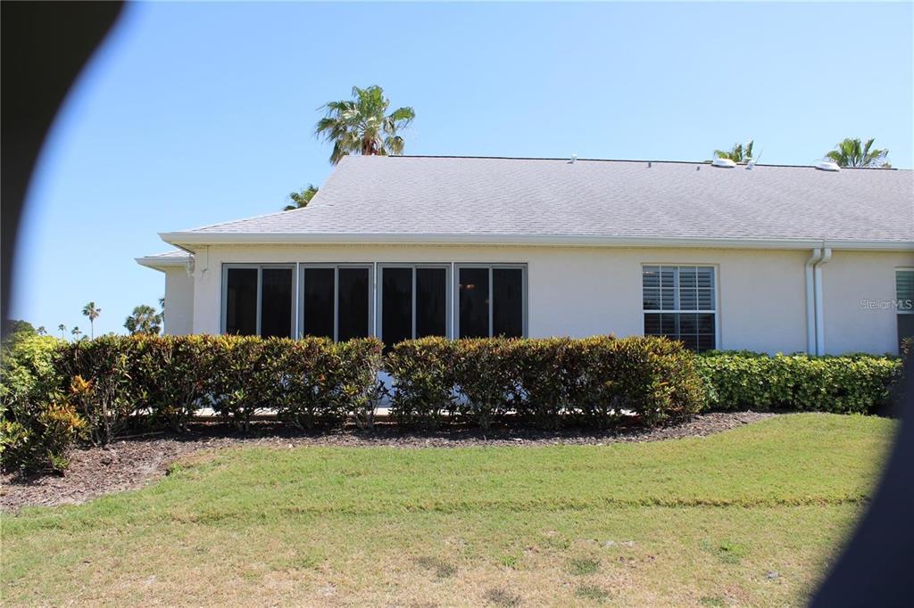 The exterior of a house features a screened-in patio, a window, and a landscaped hedge — 1702 FAIRWAY TRACE UNIT 1702, PALMETTO, FL