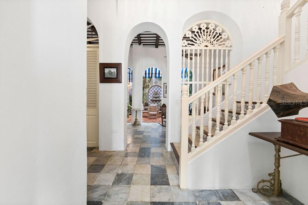 A tiled hallway leads through an arched doorway toward a courtyard with a staircase nearby — 50 SAN FRANCISCO ST, SAN JUAN, PR